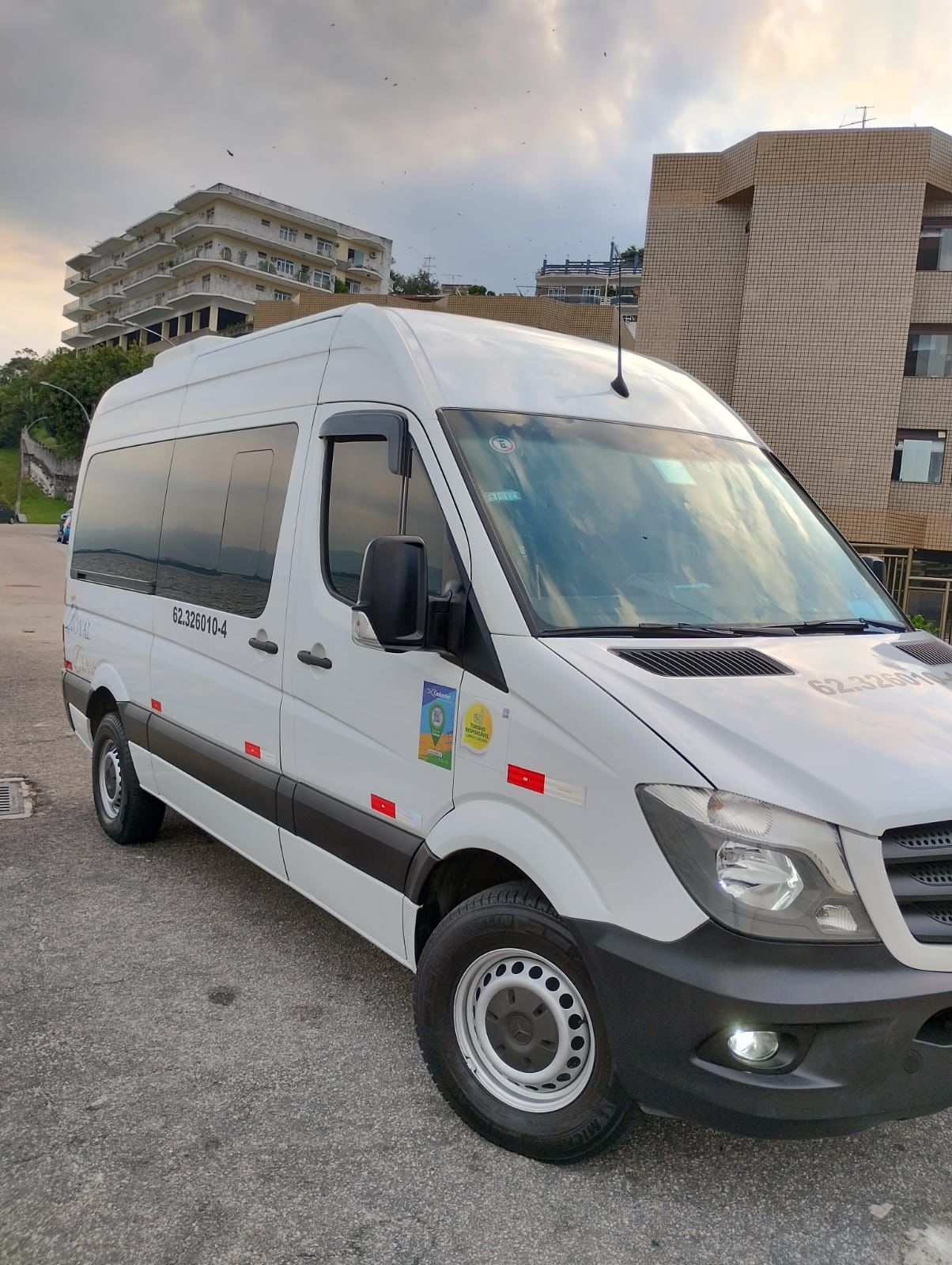 Van branca Mercedes-Benz Seventy Trans Log estacionada ao ar livre em área urbana ao entardecer.
