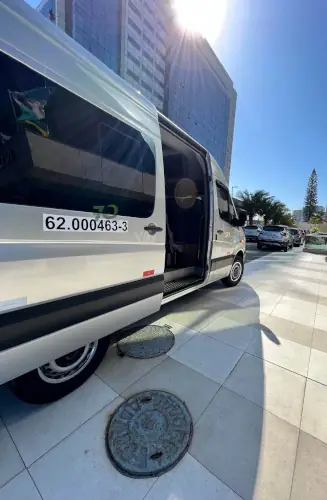Van da empresa Seventy Trans Log estacionada em frente a um prédio comercial sob sol forte